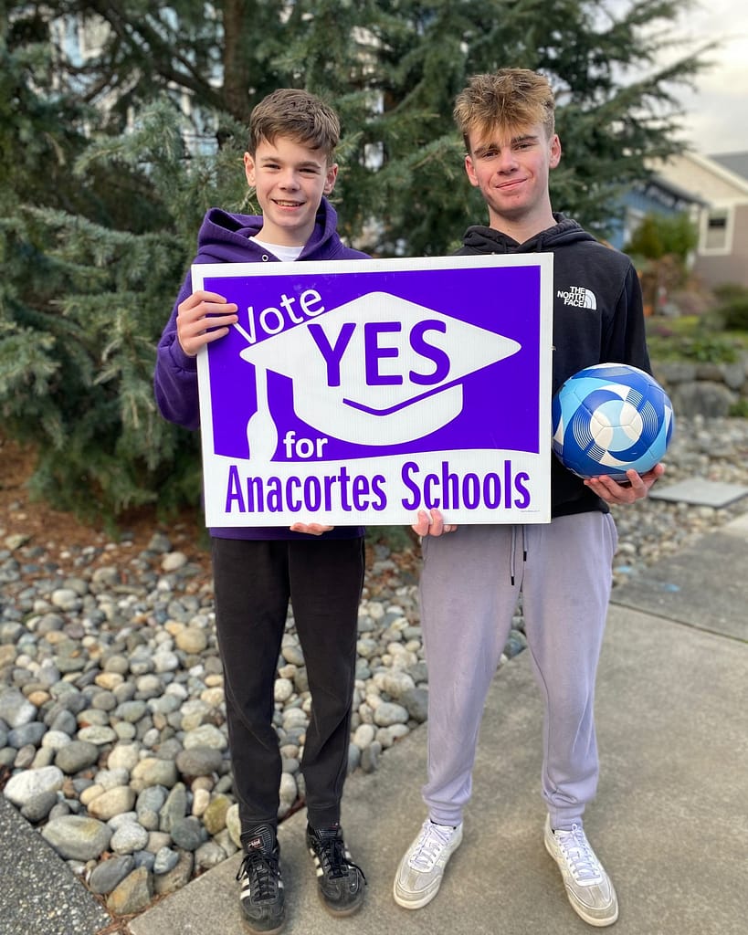 The Moroney boys hold a sign saying "Vote YES for Anacortes Schools."